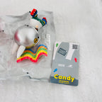 A collectible toy figure of Candy the Monster from Pop Mart, still in its clear plastic blister packaging, displayed next to its grey and yellow cardboard card on a white textured background.