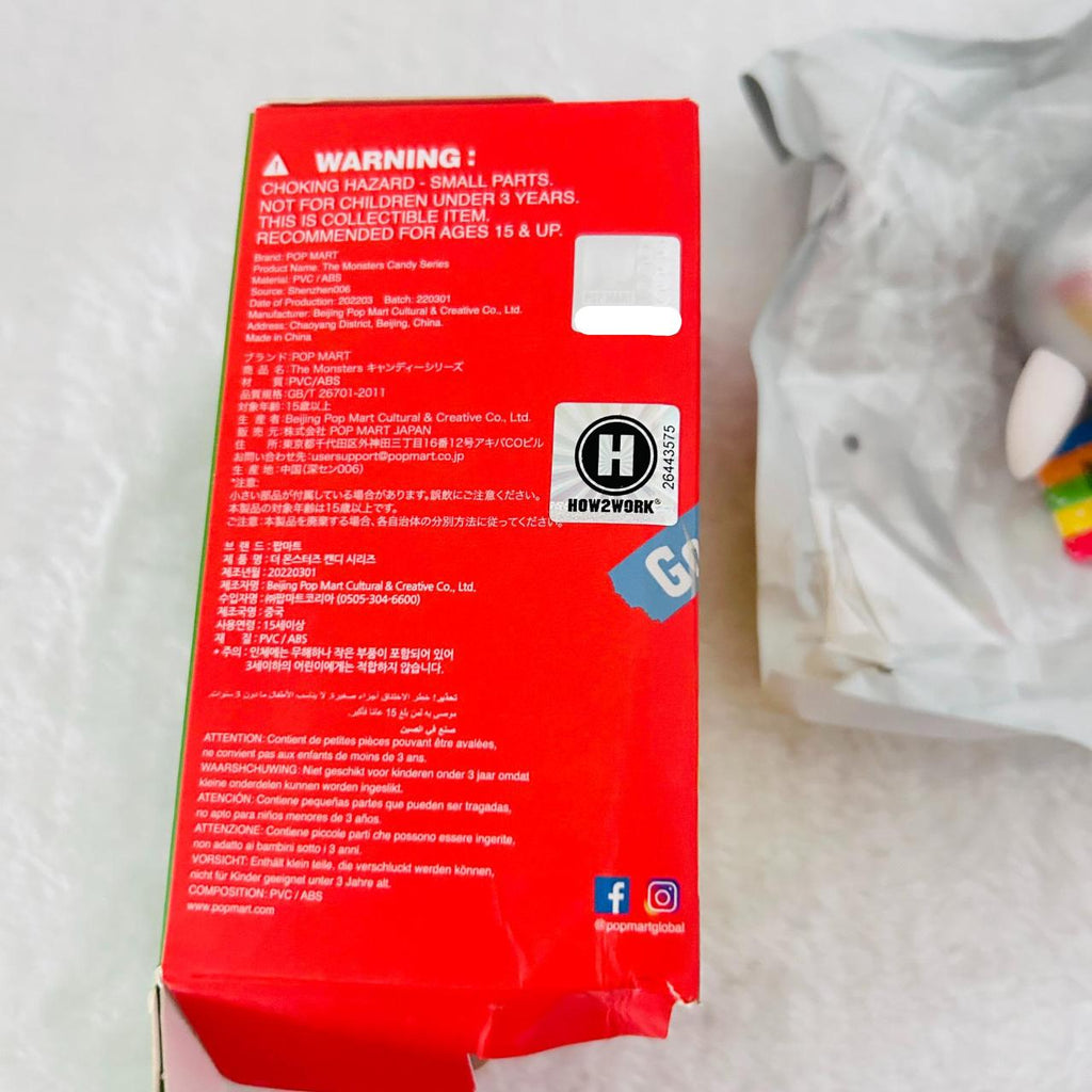 A red product box showing warning labels, and social media icons, photographed on a light surface with a white plastic bag partially visible in the background.