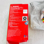 A red product box showing warning labels, and social media icons, photographed on a light surface with a white plastic bag partially visible in the background.