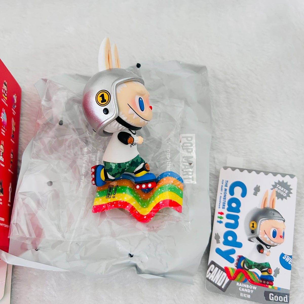 A Pop Mart Candy Bunny collectible figure in its clear plastic packaging, displayed next to its retail box on a white textured background.