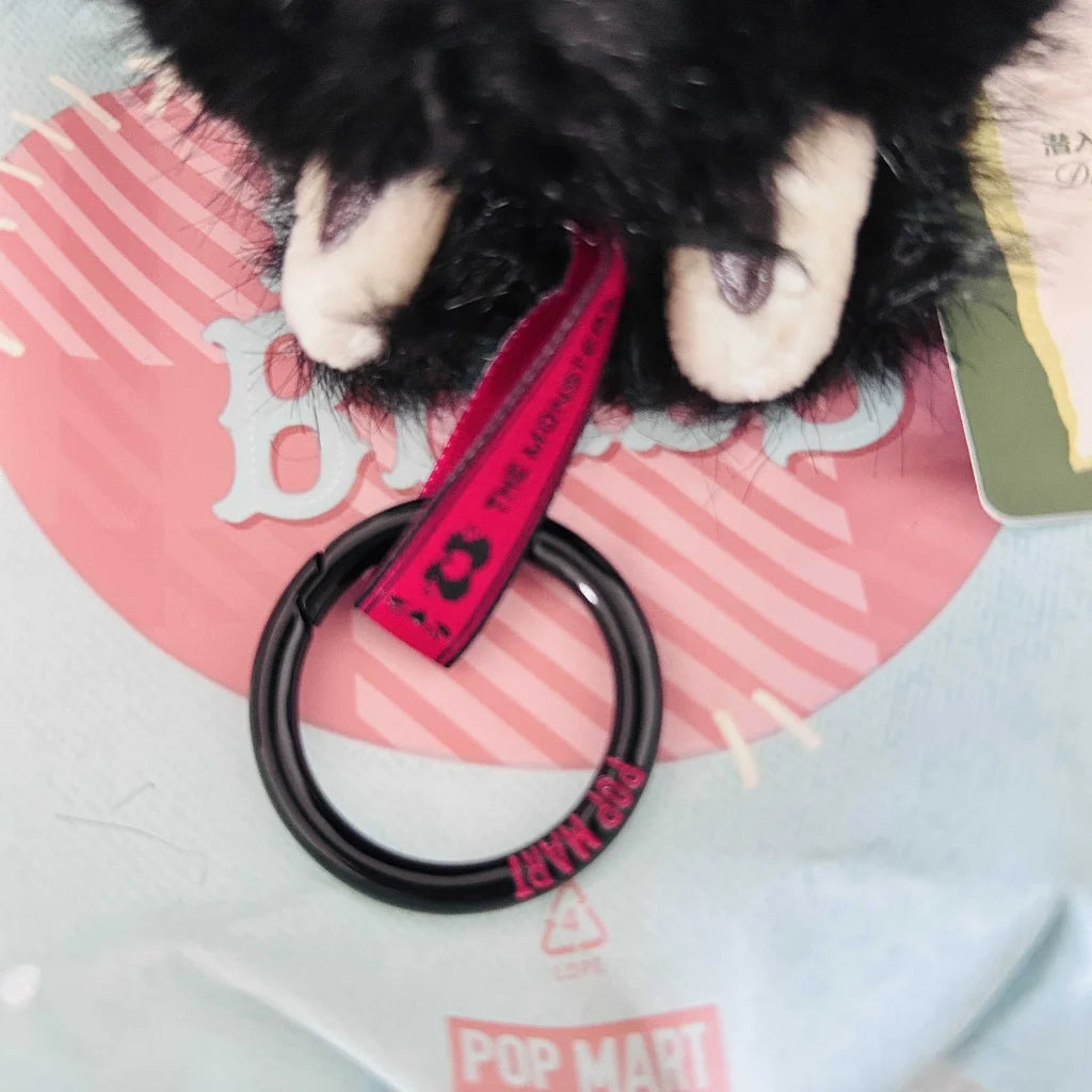 A close-up view of a Labubu plush toy chain ring with text of "POP MART".