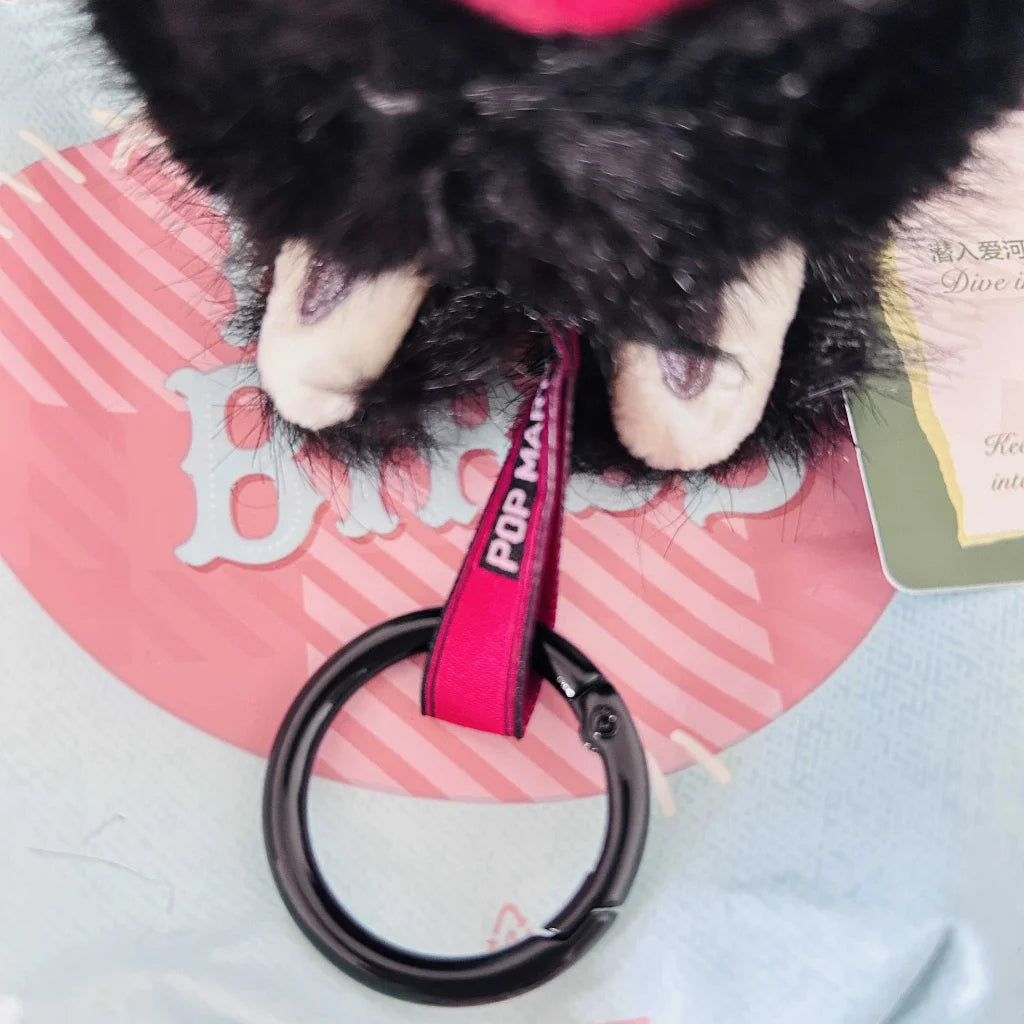 A close-up view of a Labubu plush toy chain ring with text of "POP MART".