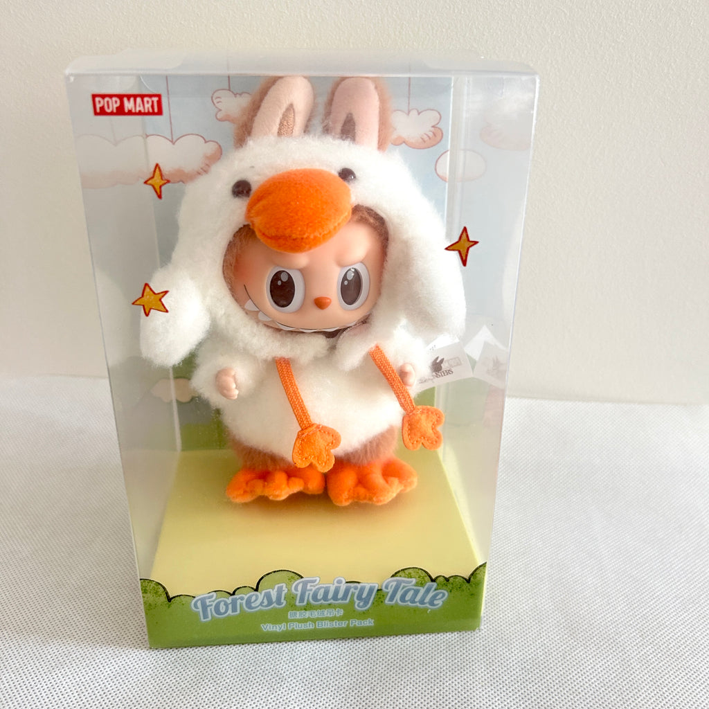 A Pop Mart Forest Fairy Tale collectible plush toy inside its original clear plastic packaging box, featuring a character in a white bunny costume with orange accents.