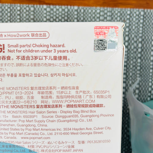 A close-up of a printed product label or packaging insert showing text, a QR code, and a small red warning seal, photographed on a gray textured surface.