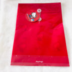 A red Joytop Hello Kitty file folder with a clear plastic sleeve, featuring a red hanging tag with the Hello Kitty character and a white textured background.