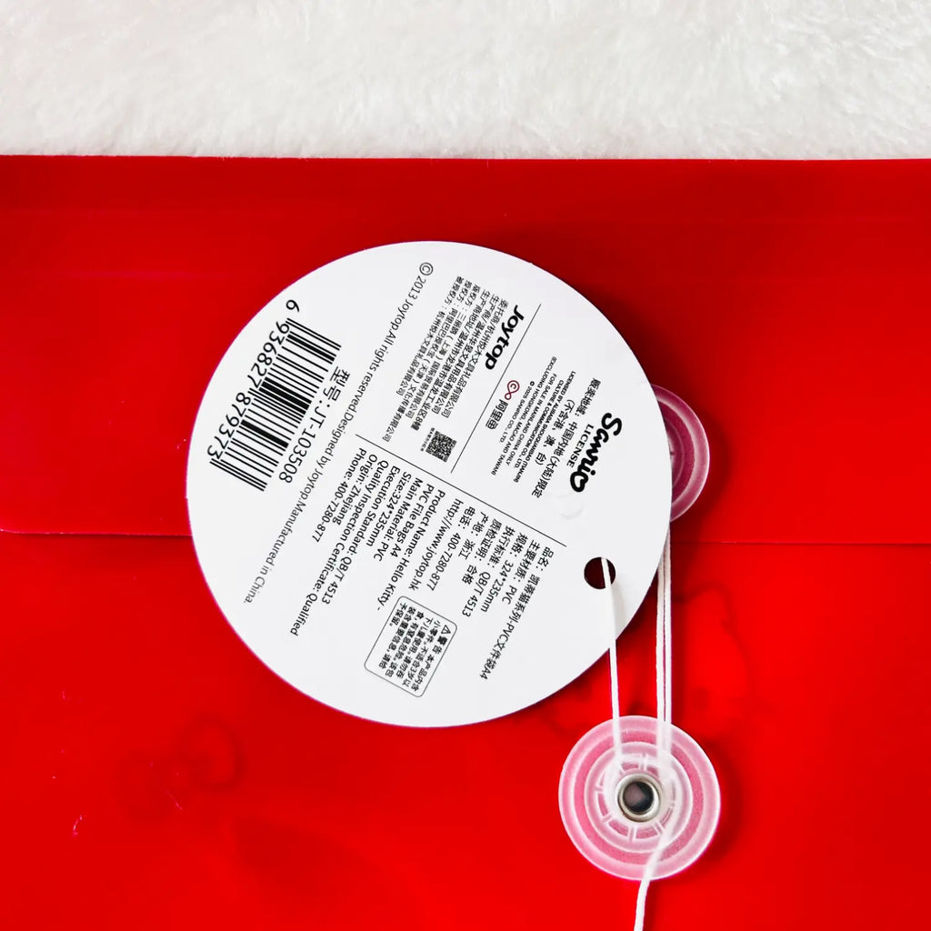 A round white product tag with printed text and barcode attached to a red item, with a clear plastic grommet and white string. The tag shows the brand name 'Simplicity' and 'Made in China' text.