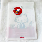 A translucent white Joytop Hello Kitty file pouch with a red round hang tag, placed on a white textured fabric background.