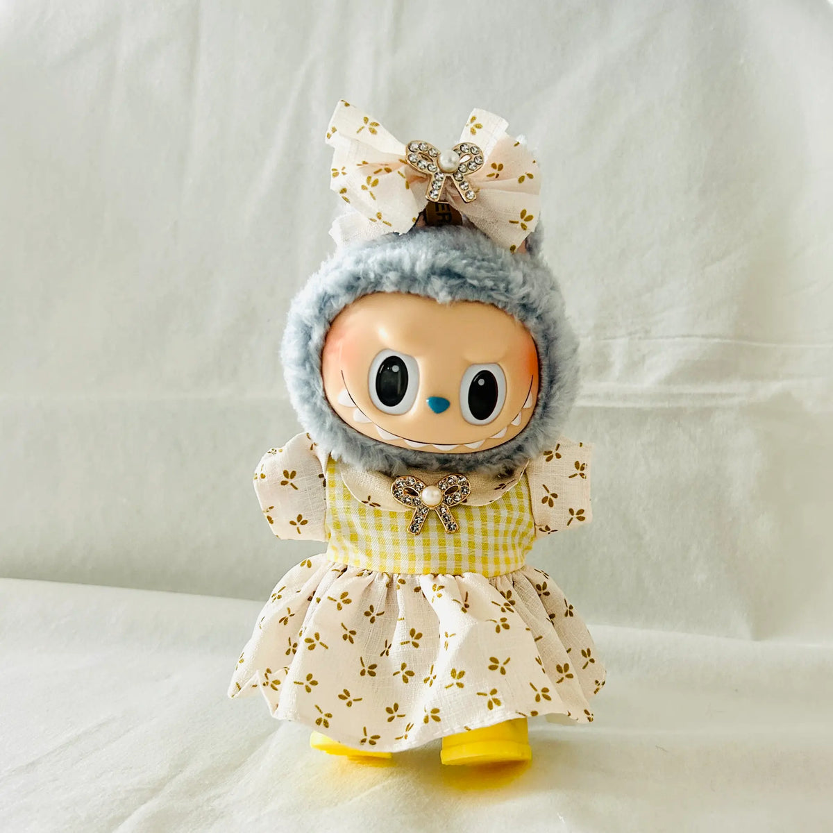 A Labubu plush doll wearing a yellow floral dress with a matching bow.