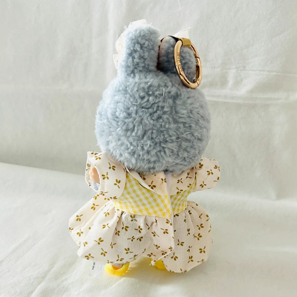 A back view of a Labubu  plush doll wearing a yellow floral dress. 