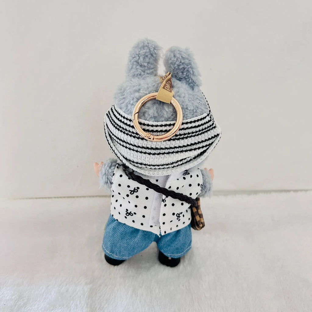 A back view of a Labubu wearing black and white striped knit hat, a white polka-dot vest, and blue denim pants.