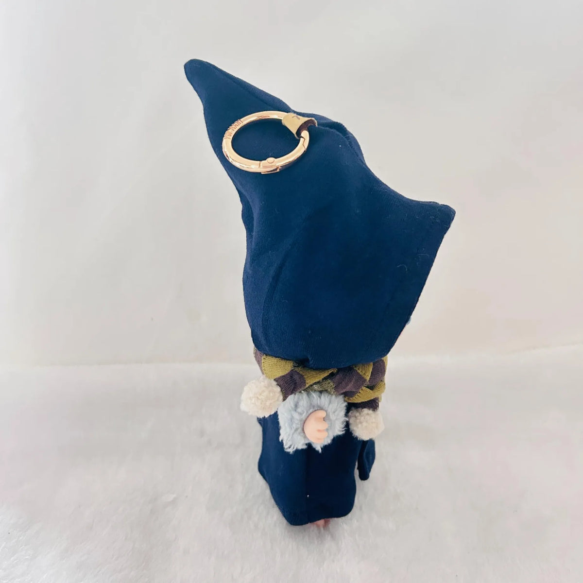 A small wizard or gnome figurine with a tall dark blue pointed hat, a patterned scarf.