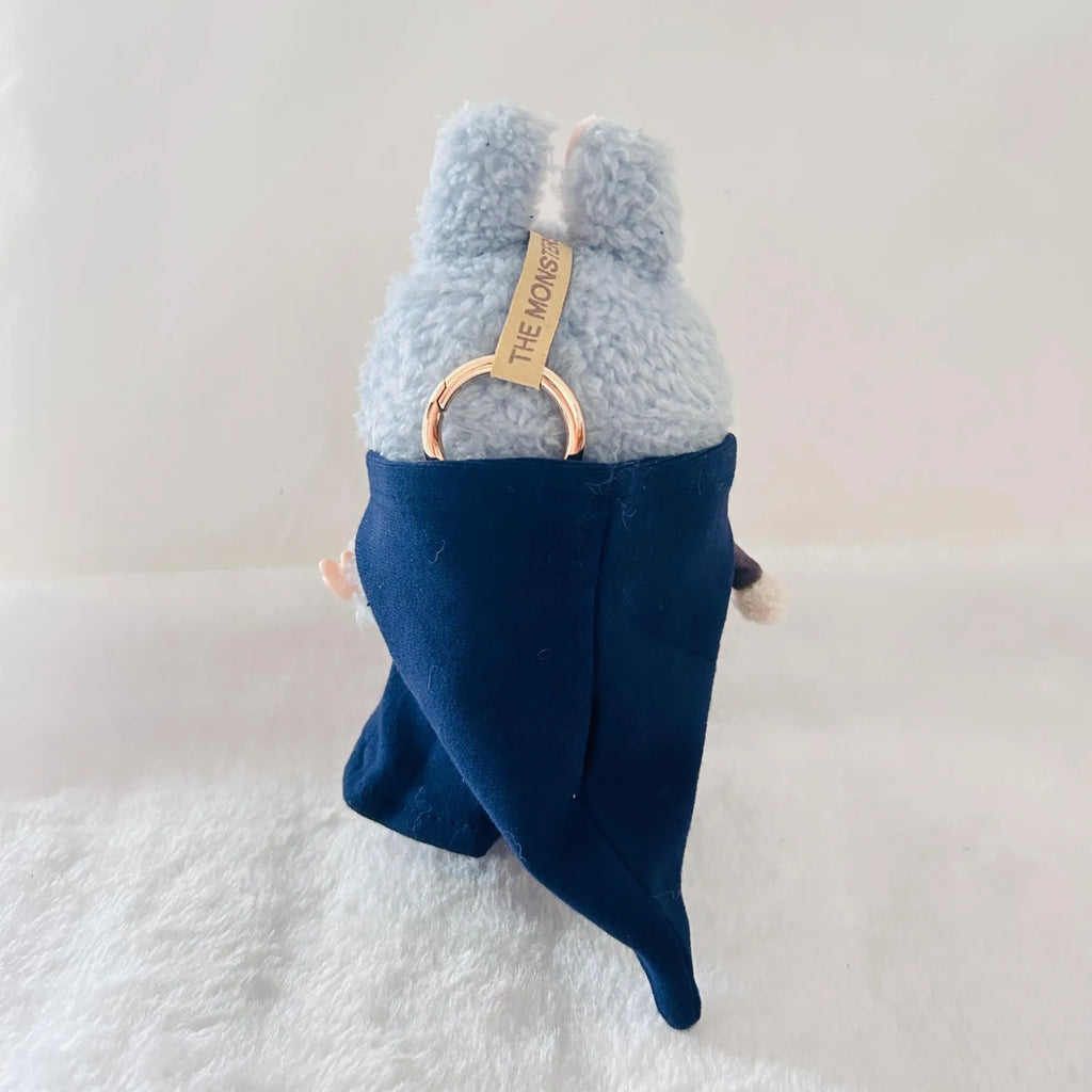 Back view of a  Labubu doll wearing a dark navy cape.