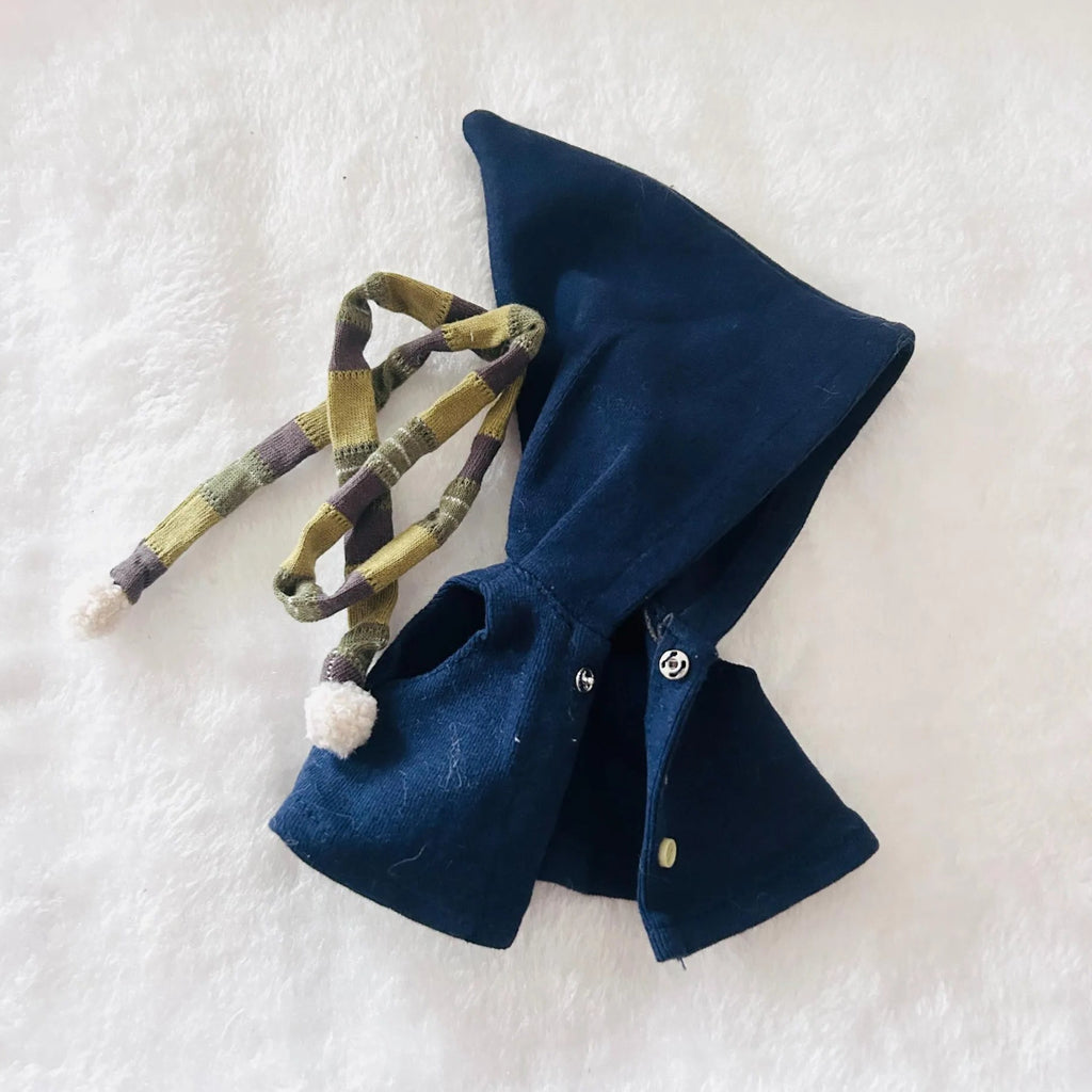 A dark navy blue cape with a plaid green and yellow drawstring and a small white pom-pom.