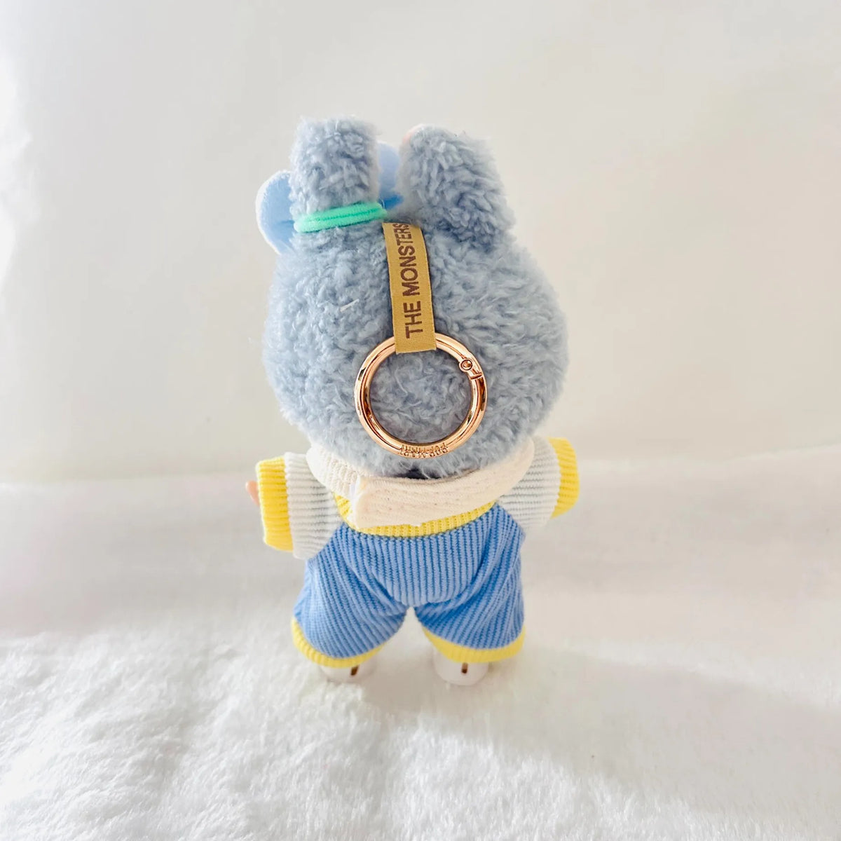 Back view of a Labubu plush wearing a cream and blue striped outfit.