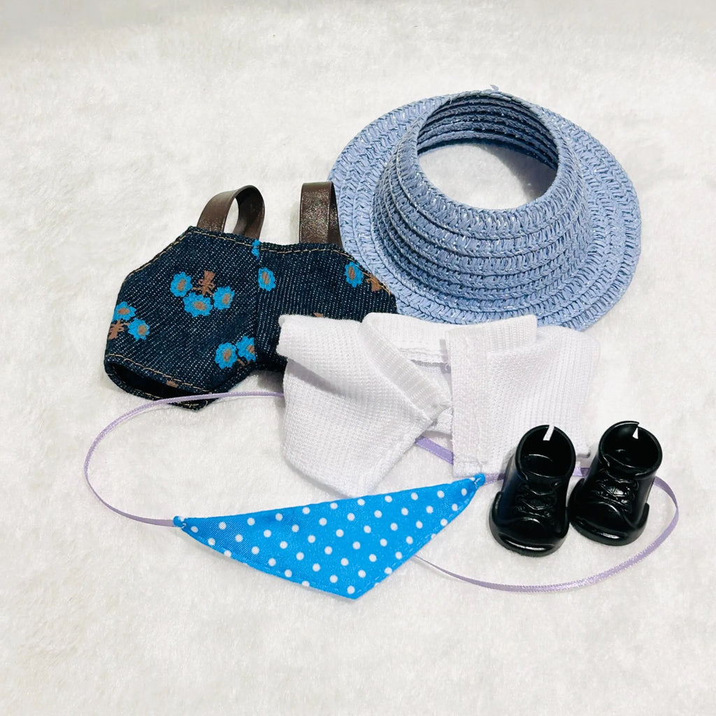 A back view of doll outfit set including a blue straw sun hat, a dark denim-style vest with blue floral print, a white shirt, a bib, and a pair of black booties.