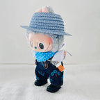 A stylized Labubu plush doll has a blue woven hat, a blue polka-dot bandana, dark blue patterned pants, and black shoes.