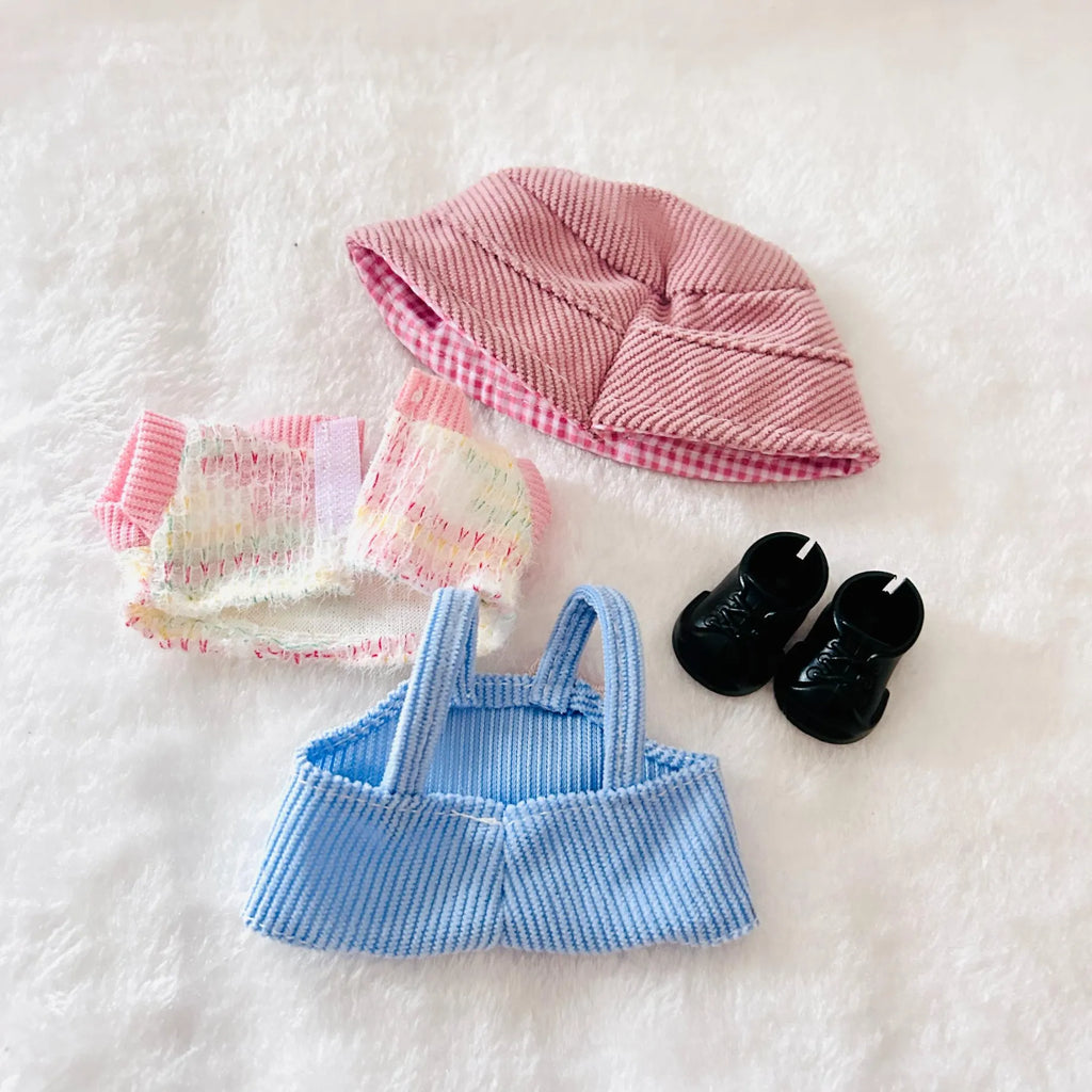 A back view of a doll clothing set, including a pink hat, a pastel striped pants, a light blue striped top, and black shoes.