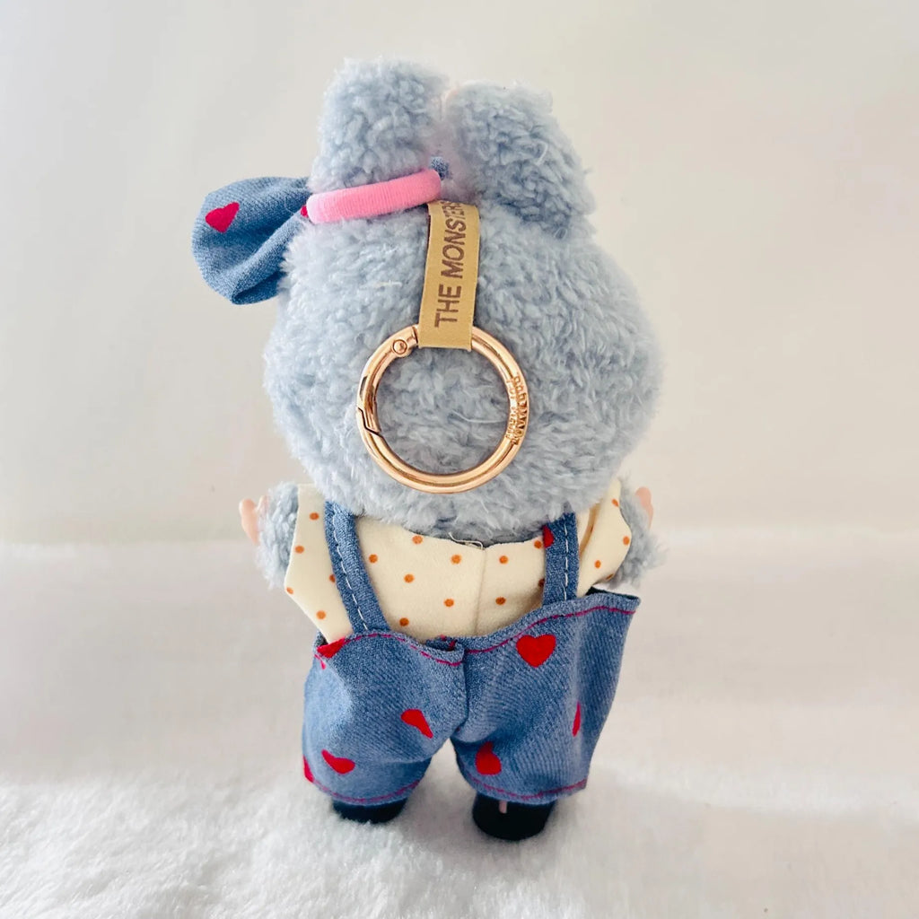 A back view of a Labubu plush doll wearing a denim overalls with red hearts, a cream polka-dot shirt.