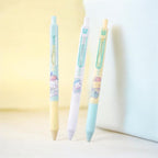 Three pastel retractable gel pens with cute cartoon character illustrations, standing upright on a light surface against a soft yellow and white background.