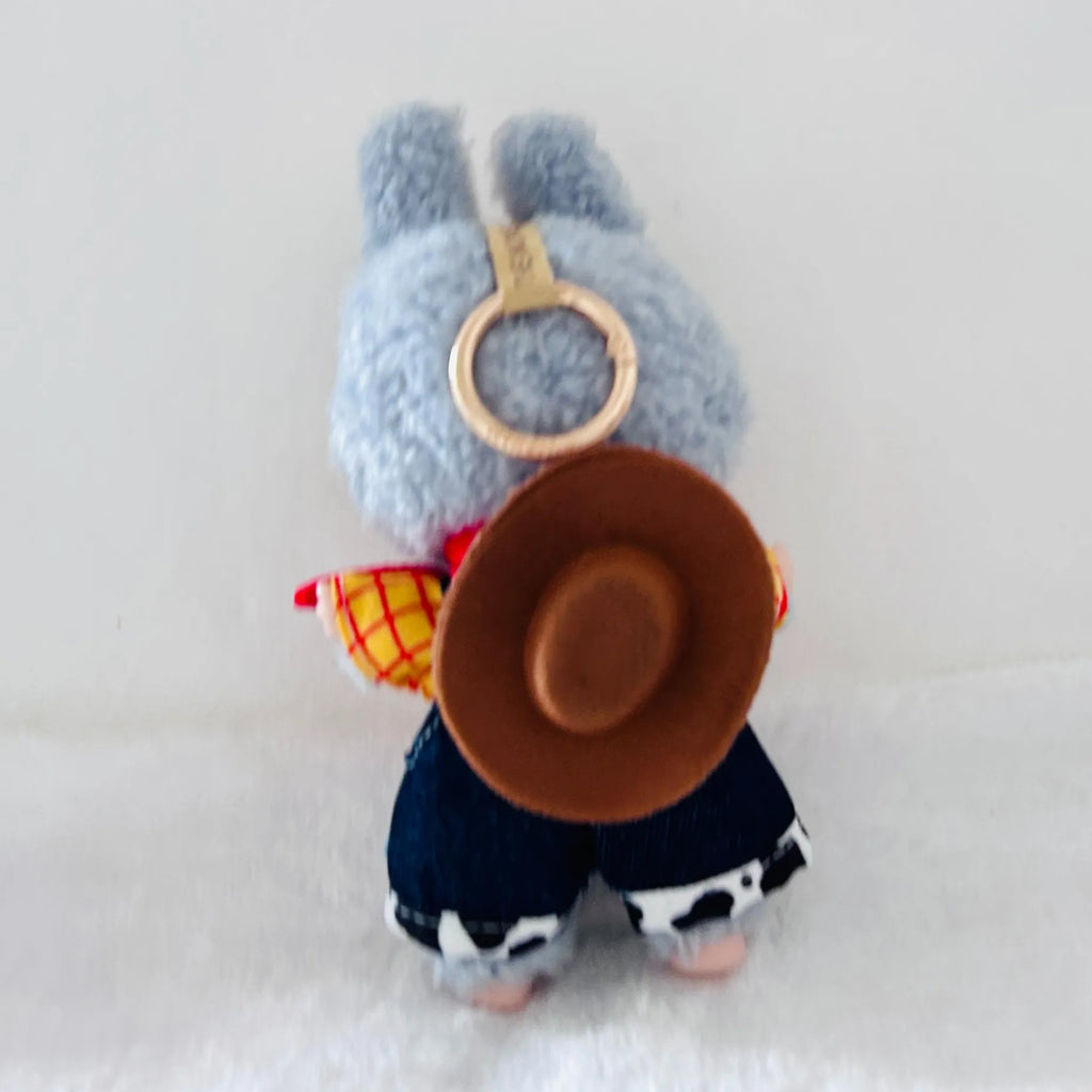 A back view of a Labubu plush wearing a brown cowboy hat, a red and yellow plaid shirt, and dark blue pants.