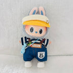 A Labubu plush doll wearing a cream ribbed cap, blue denim-style overalls with brown suspenders, a navy-and-white striped shirt, and white shoes.