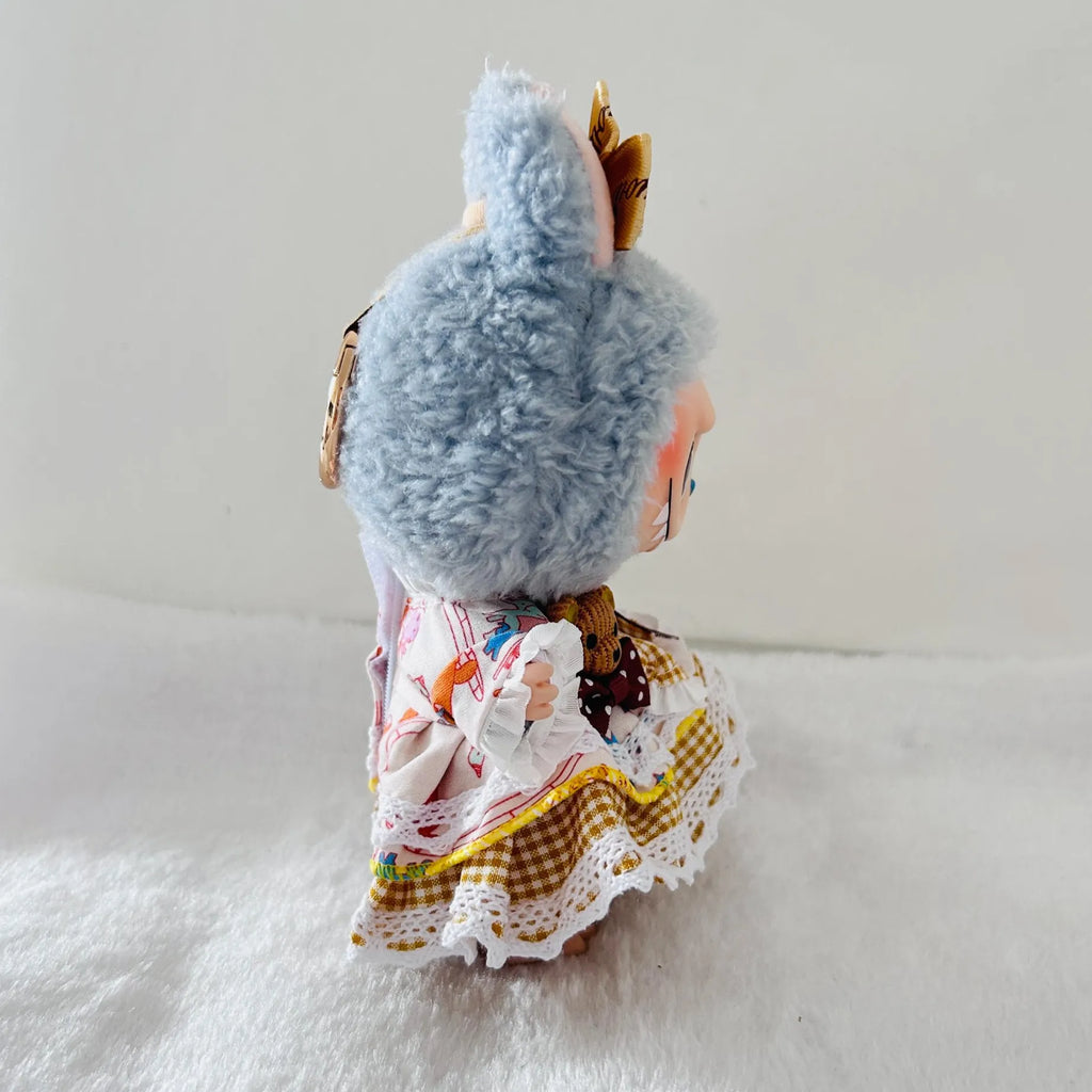 A Labubu plush doll wearing a patterned white dress with lace trim, and gold accessories.