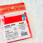 A red plastic folding mirror in its clear plastic packaging, featuring a white label with Chinese text, a barcode, and the 'Sanrio' brand logo, set against a white textured background.