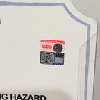 A close-up of a white plastic retail display card with a blue border, showing a small Pop Mart holographic security sticker near the center.