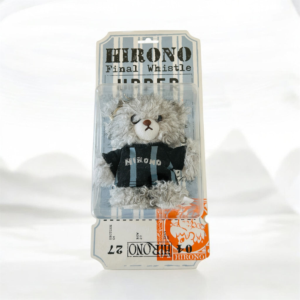 A packaged plush toy resembling a gray furry character wearing a black shirt with blue stripes and the word 'HIRONO' on the front, mounted on a printed backing card.