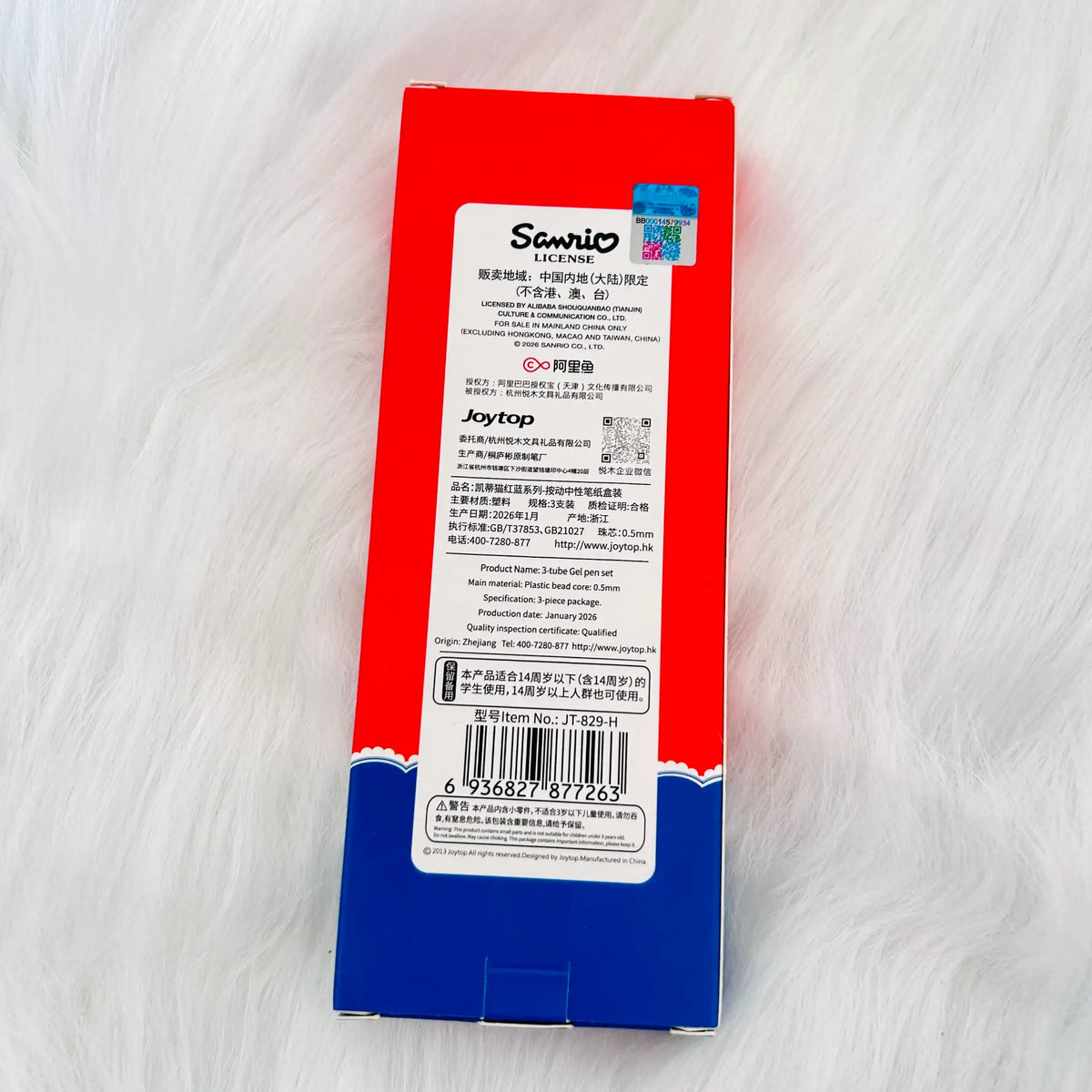 The back of a red and blue product box with a large white label containing text, a barcode, and a small QR code, photographed on a white furry surface. Visible branding on the label includes Senrio and Joytop.