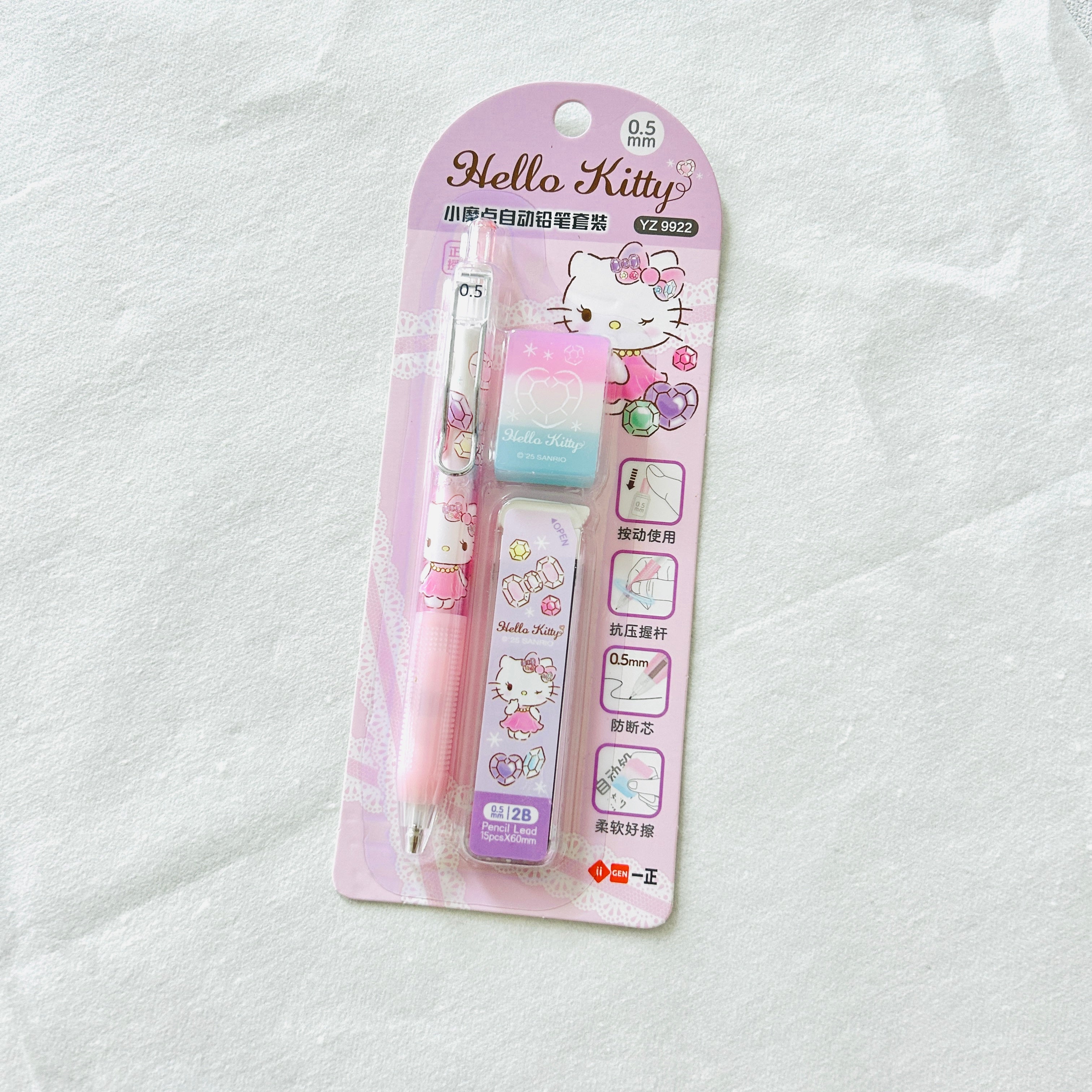 Hello Kitty 0.5mm retractable pen set in pink blister packaging, featuring a pink pen, a pastel blue and pink eraser, and a purple eraser cover on a white textured fabric background.