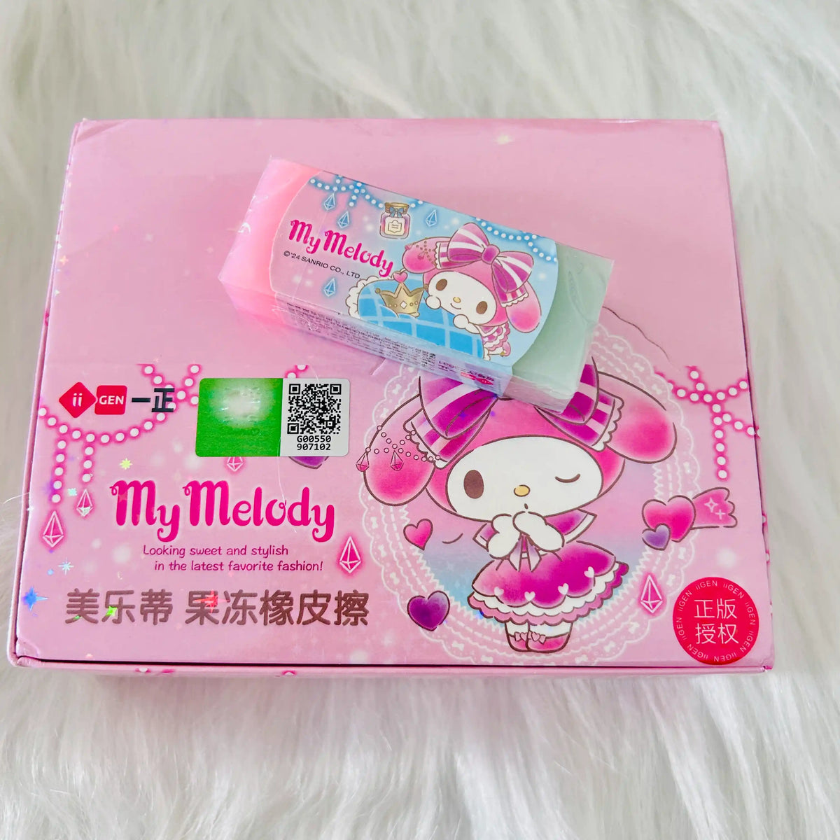 A pink and green My Melody eraser placed on it's package box with QR code. 