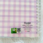 A close-up of a spiral-bound notebook with a pink and white gingham patterned cover, featuring a Sanrio License sticker.
