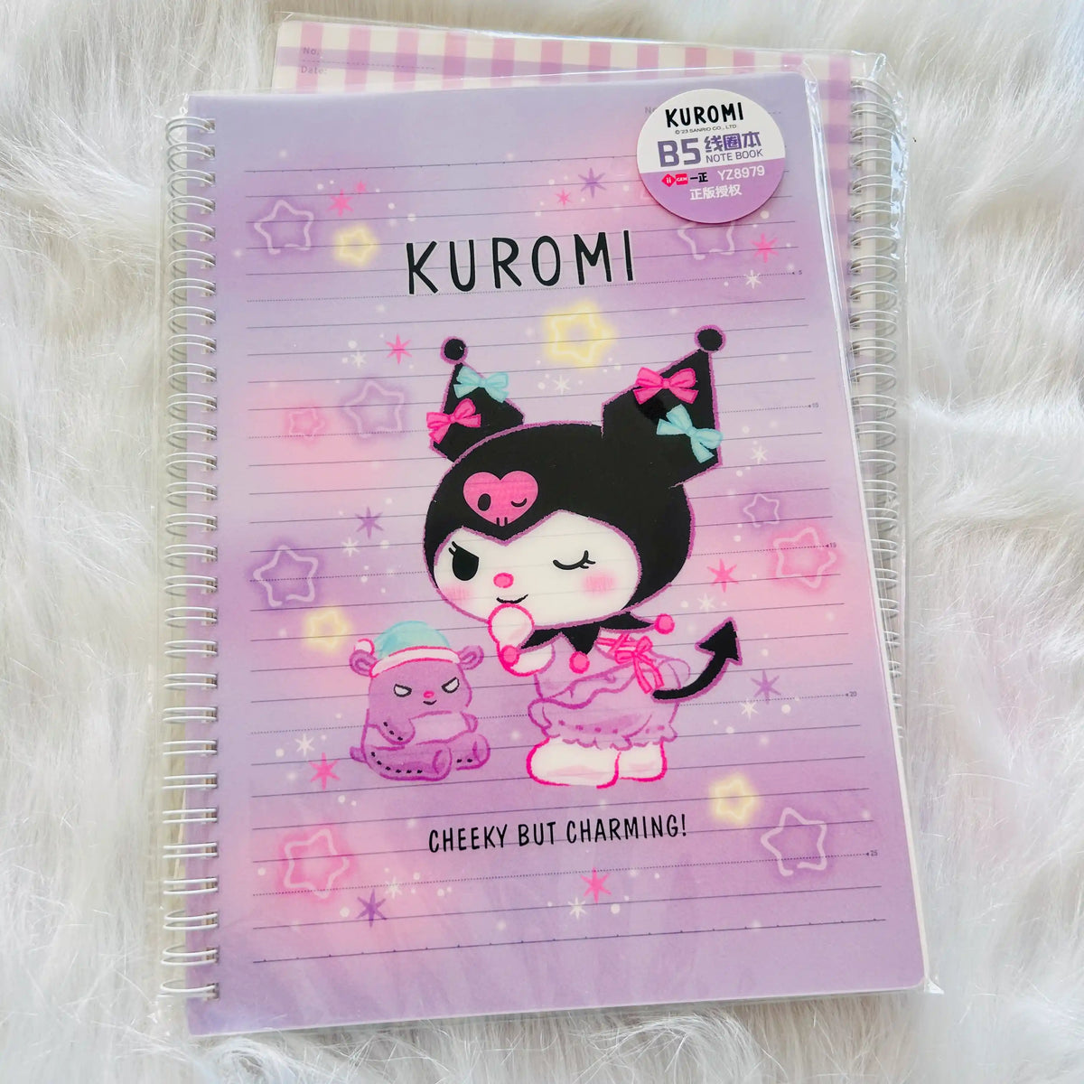 A Kuromi-themed spiral-bound notebook with a pastel purple cover, featuring a cartoon character illustration and the text 'KUROMI' and 'CHEEKY BUT CHARMING!'.  