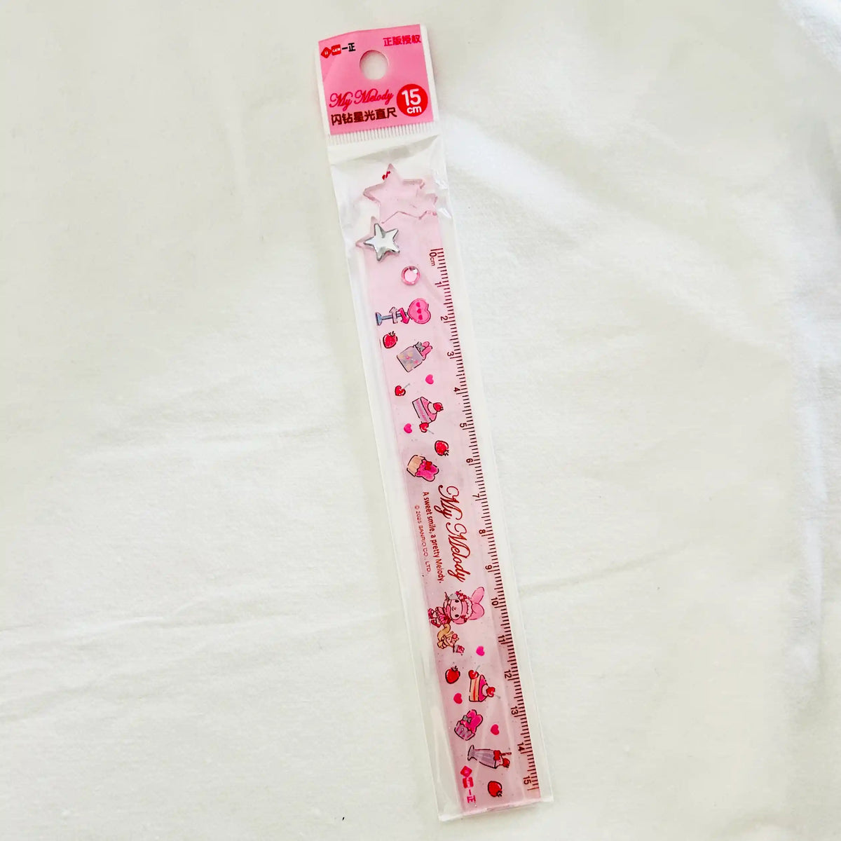 A pink My Melody plastic ruler in its clear plastic packaging, featuring cute illustrations of cakes, hearts, and stars.