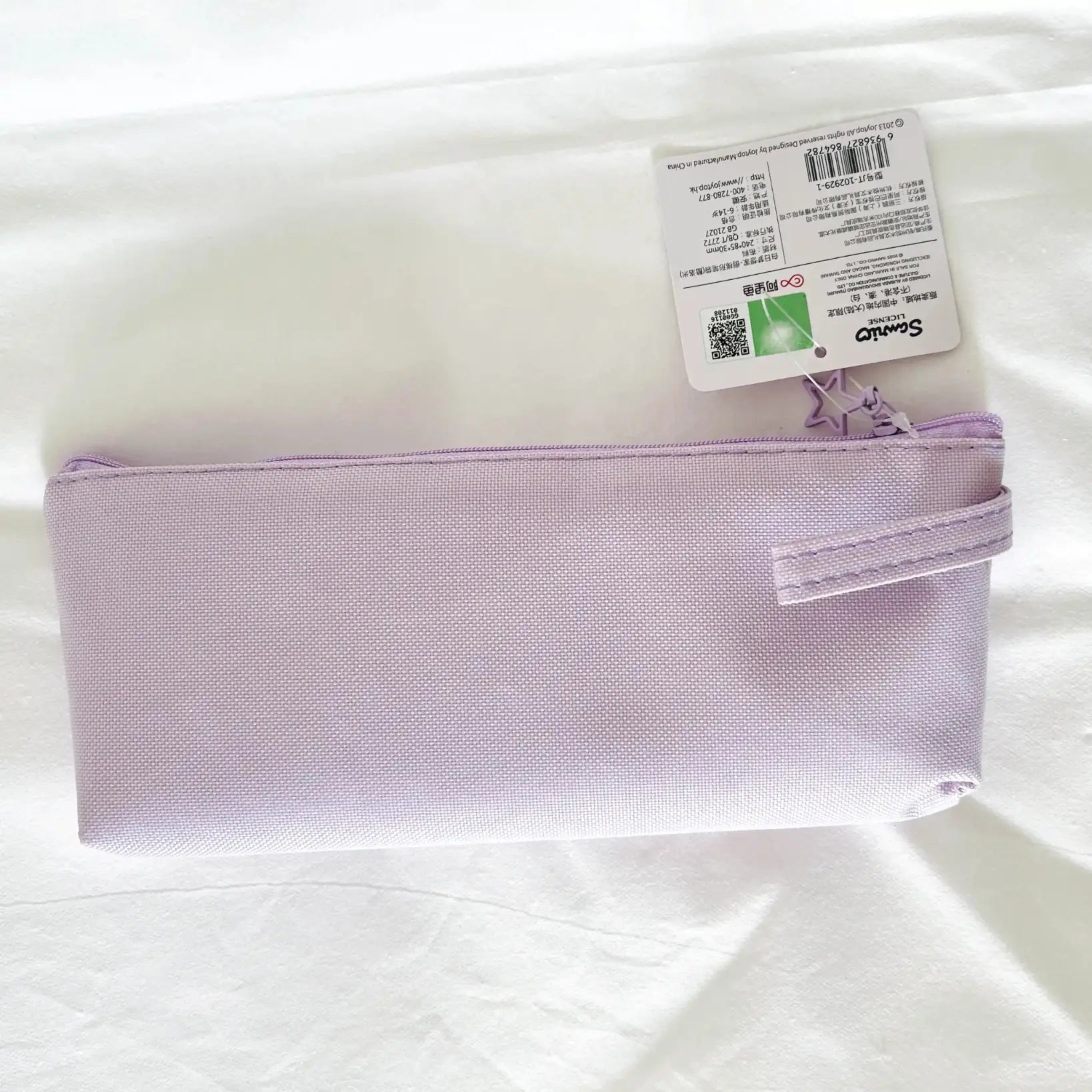 A light purple canvas zippered pouch with a wrist strap, shown with its retail tag on a white fabric background.