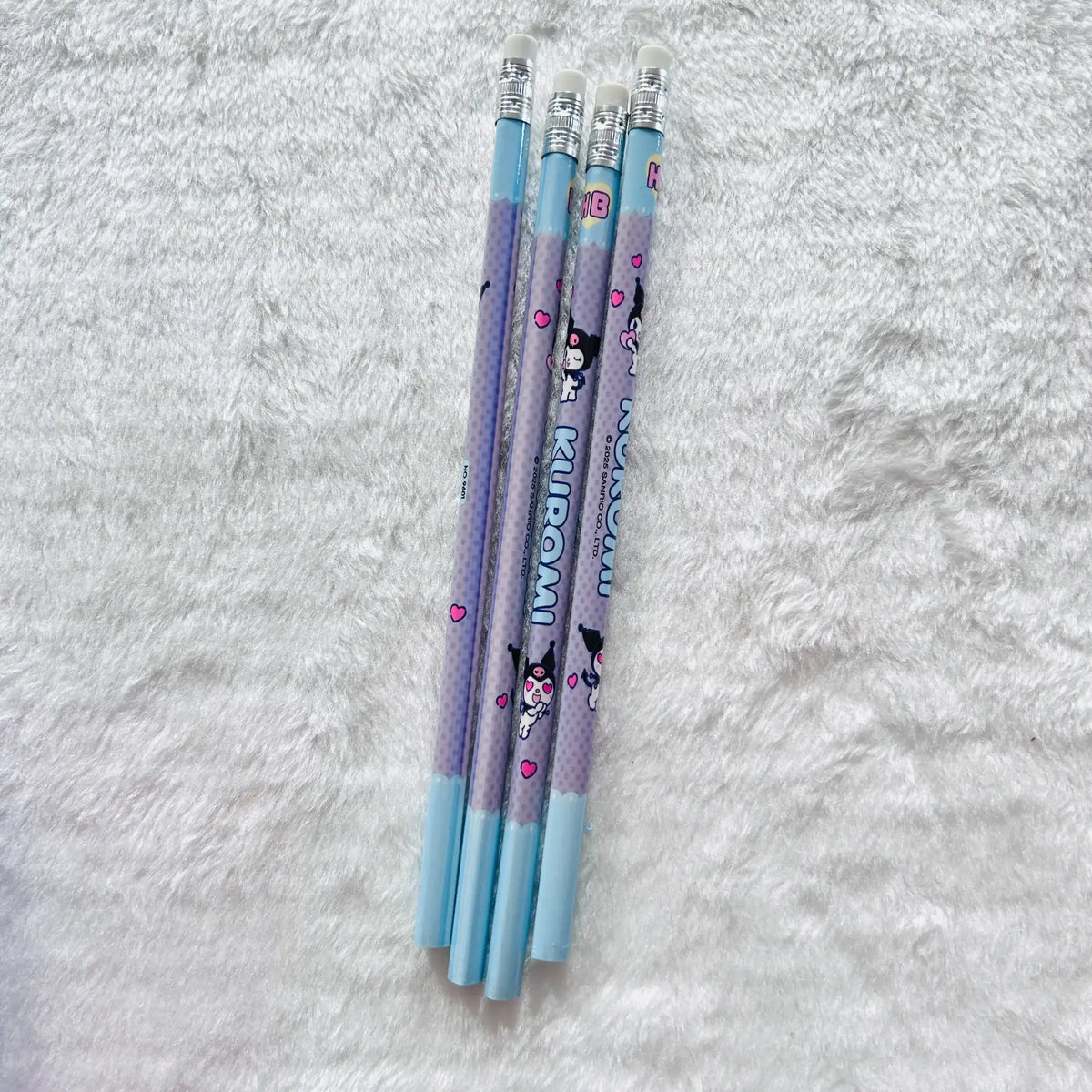 Four Kuromi-themed pencils with light blue and lavender-purple bodies, decorated with cartoon characters and the word 'KUROMI'.