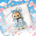A cute plush doll dressed in a light blue dress and matching bow headband, displayed inside a light wood frame.