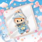 A cute plush toy doll with large black eyes, wearing a light blue denim-style outfit and matching hat with pastel rainbow and star details.