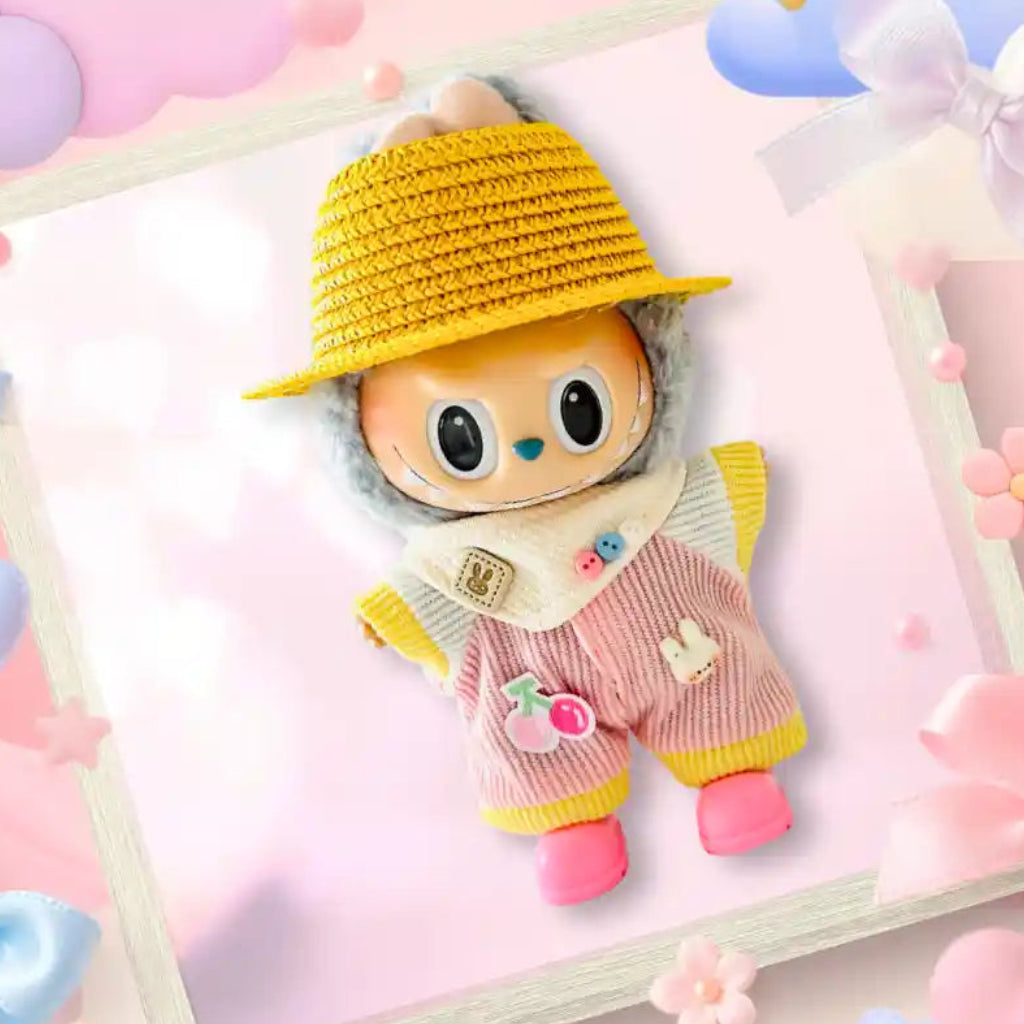 A Labubu doll wearing a pink and yellow striped jumpsuit with a cherry applique, with a yellow straw hat. 