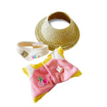 A Labubu outfit set, featuring a pink and yellow striped jumpsuit with a cherry applique, with a straw hat. 