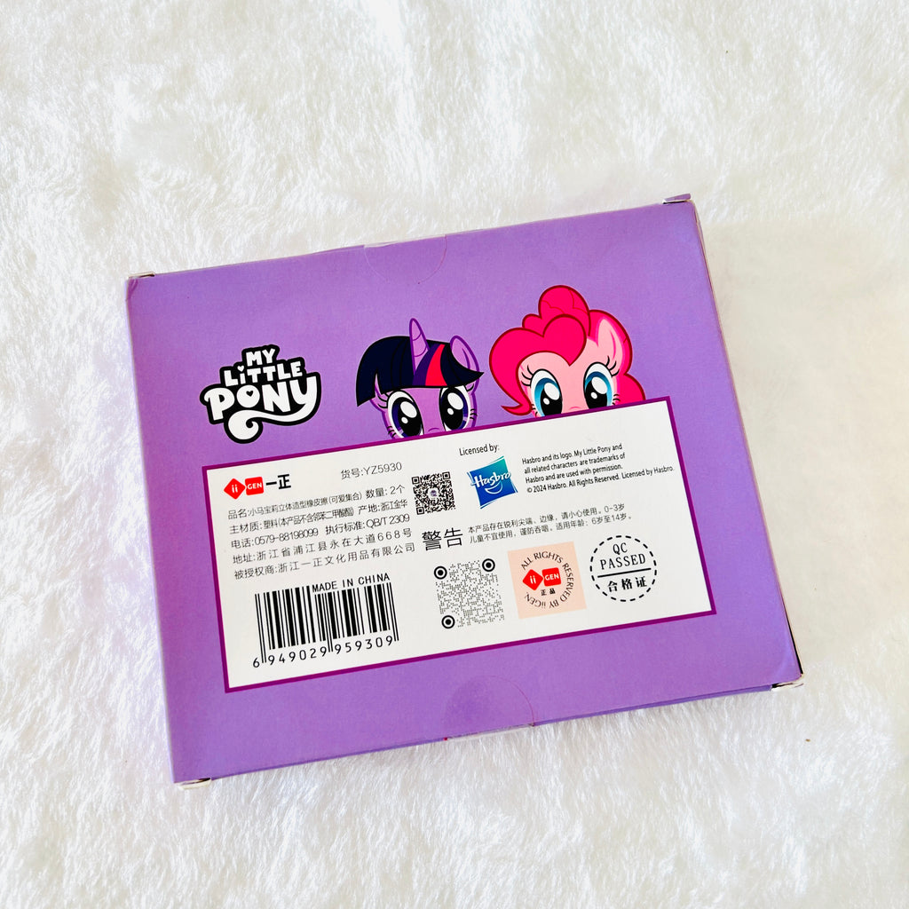 The back of a purple My Little Pony toy box, featuring character artwork of Twilight Sparkle and Pinkie Pie, with product text, a barcode, and a Hasbro logo, photographed on a white textured fabric background.
