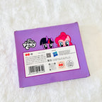 The back of a purple My Little Pony toy box, featuring character artwork of Twilight Sparkle and Pinkie Pie, with product text, a barcode, and a Hasbro logo, photographed on a white textured fabric background.