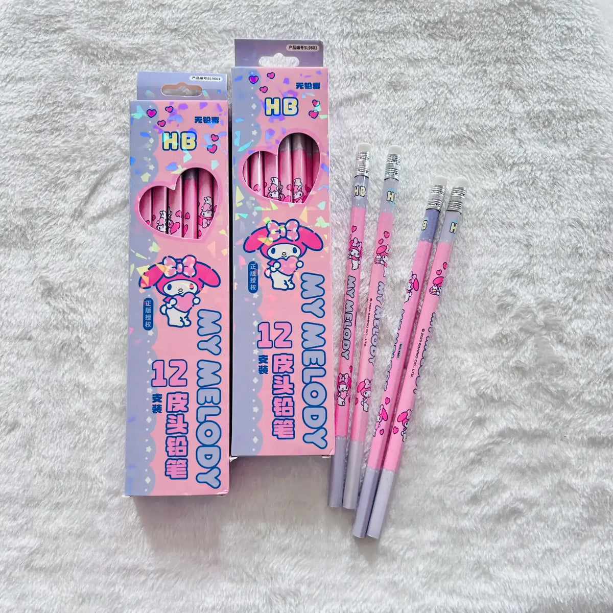 Pink and purple My Melody HB 12 lead pencil set with two retail boxes and four loose pencils on a white textured fabric background.