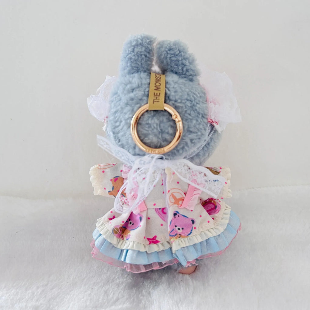 Back view of a Labubu plush doll wearing a ruffled dress with pink cartoon bear prints, white lace trim.