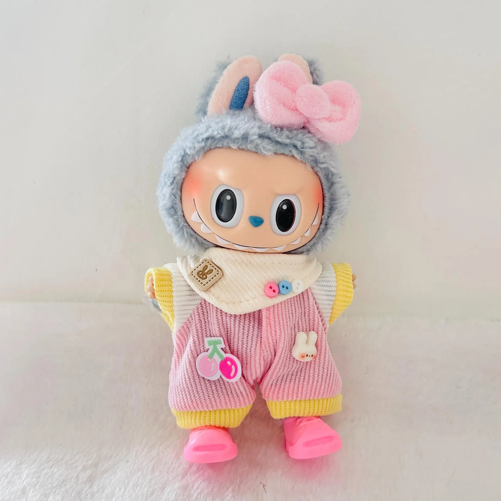 A Labubu plush doll with a pink bow, and pink striped overalls with yellow trim, standing against a soft off-white background.