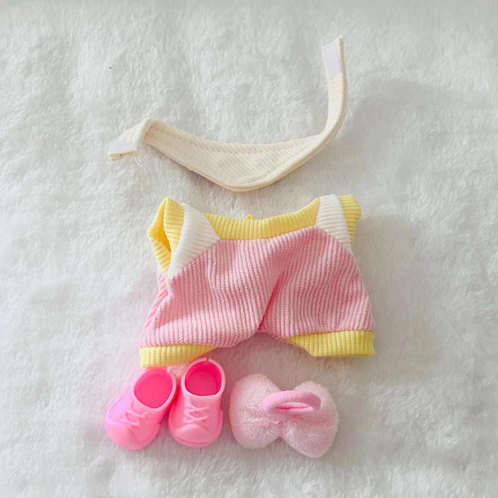A back view of a doll clothing set including a pink and yellow striped romper, pink booties, and a pink bow.