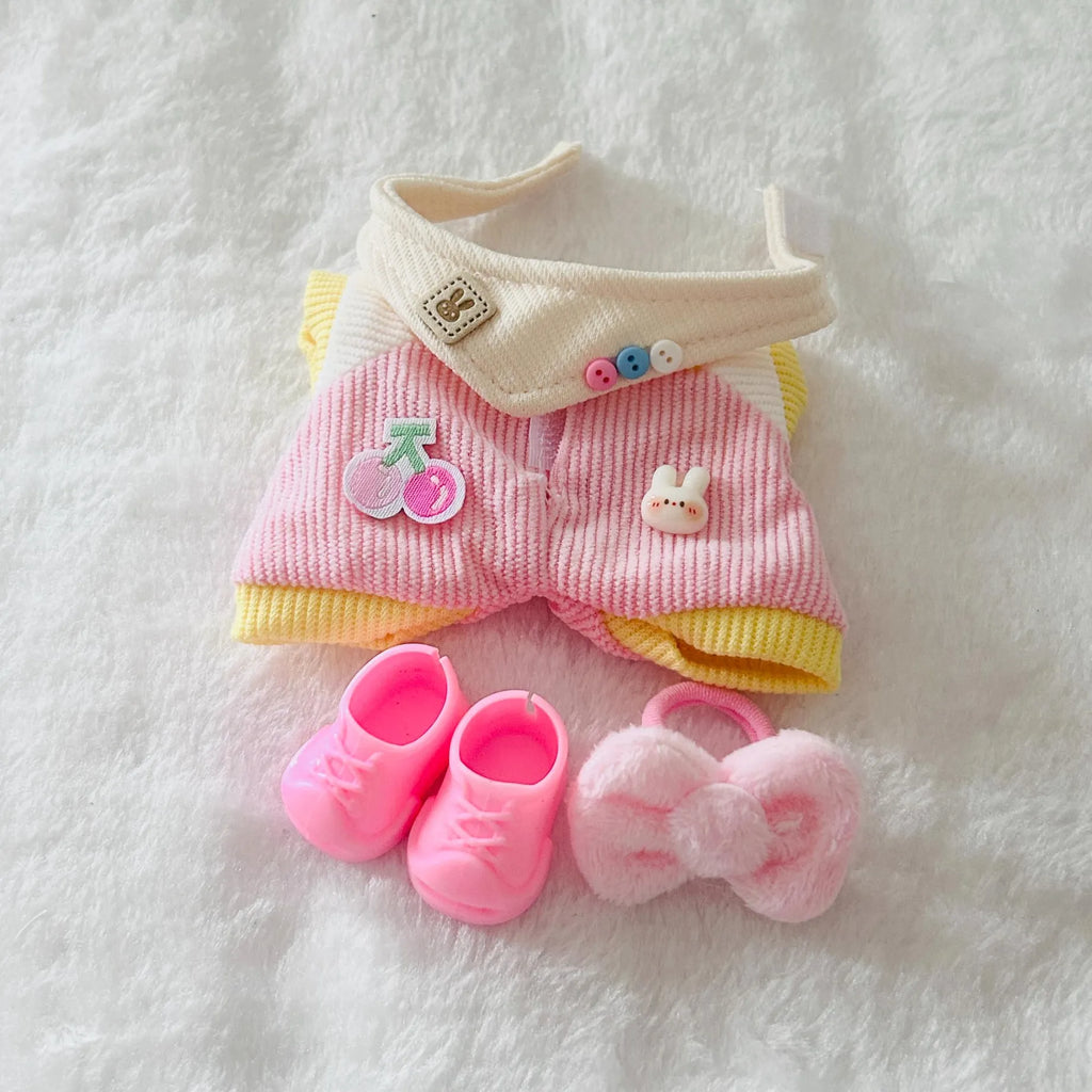 A doll outfit set featuring a pink ribbed romper with yellow trim, a cream collar, pink shoes, and a fluffy pink bow.