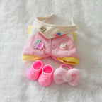 A doll outfit set featuring a pink ribbed romper with yellow trim, a cream collar, pink shoes, and a fluffy pink bow.