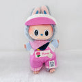 A Labubu plush doll wearing a pink visor, and pink overalls with decorative patches.